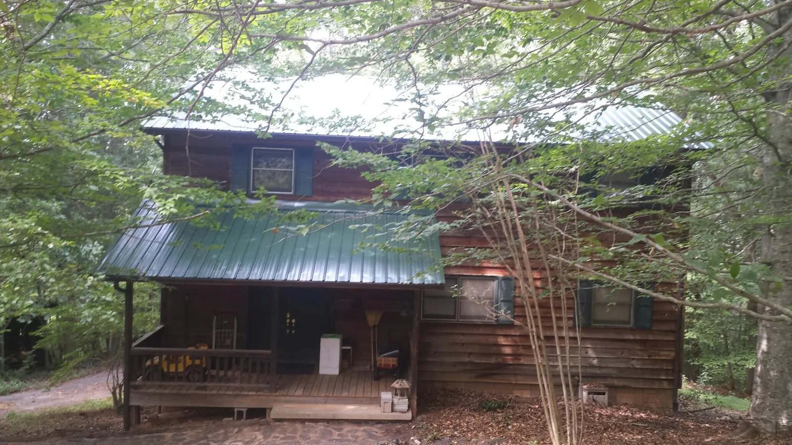 Green metal roof and covered porch on a log cabin in Gasburg