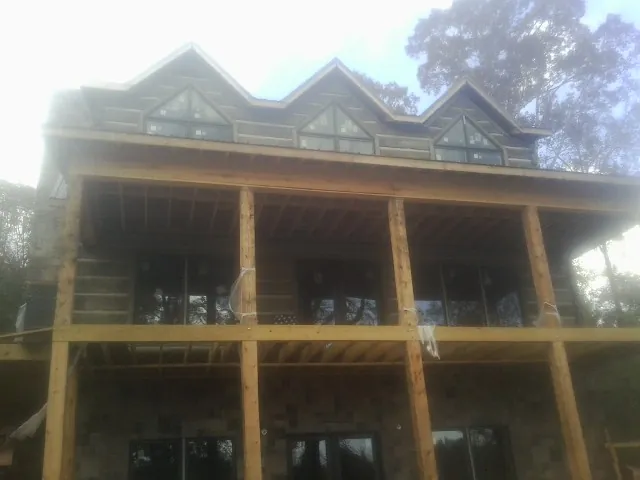 Dormers and porch framing on a large log home under construction — Roof Coating work by our crew in Gasburg
