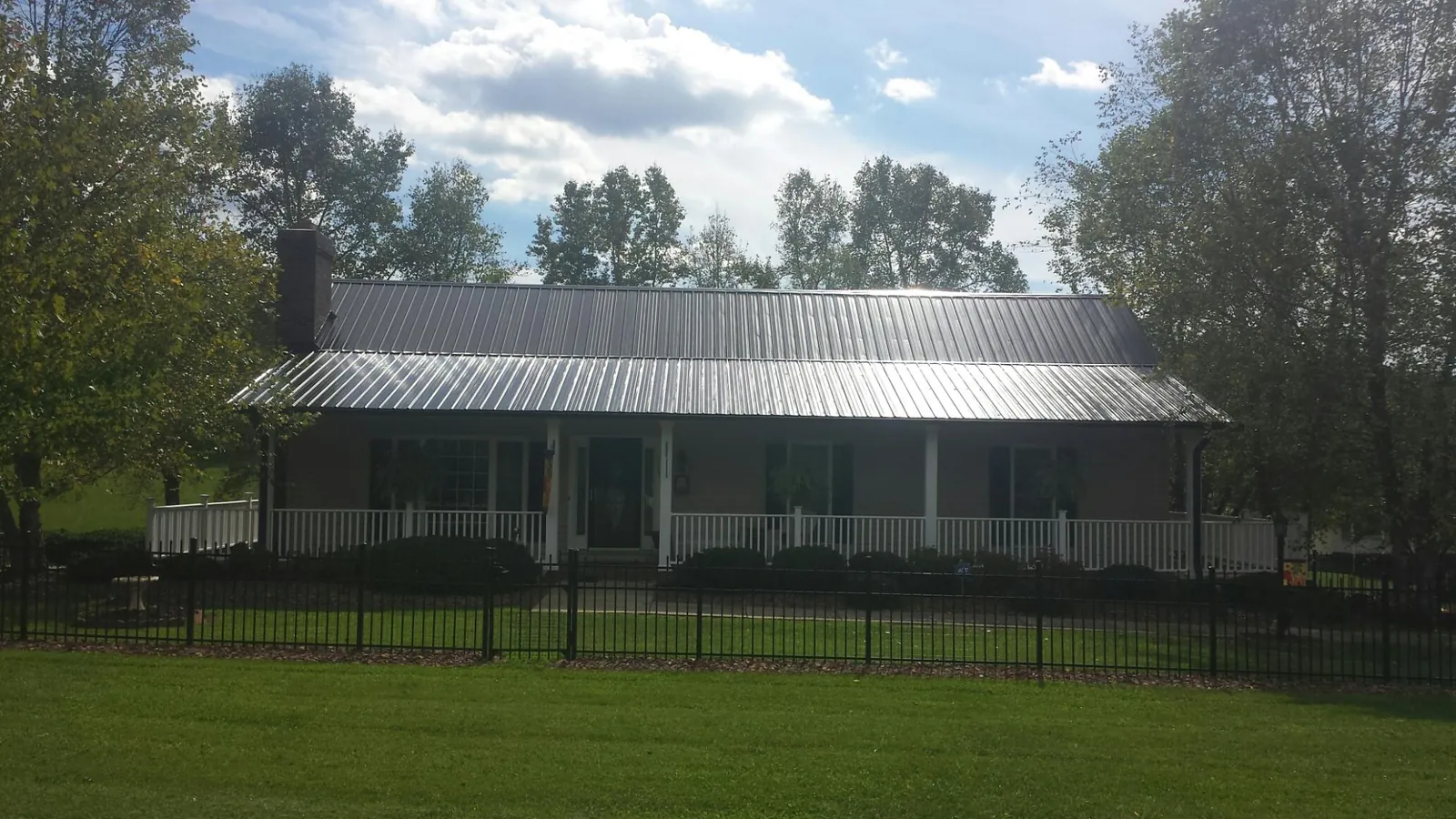 Gray metal roof on a brick ranch with a full width front porch — Gutter Guard Installation work by our crew in Gasburg