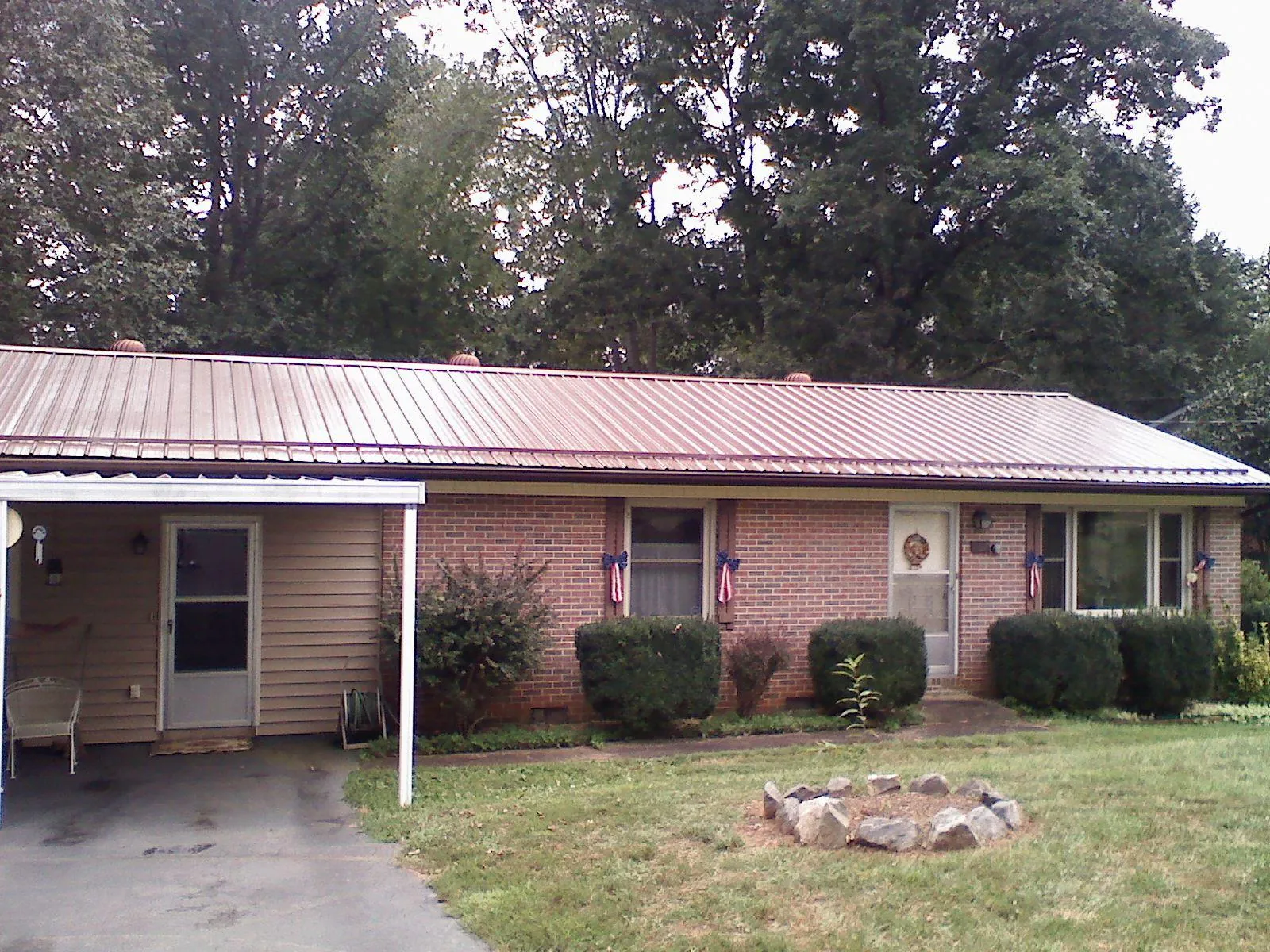Bronze metal roof and carport on a brick ranch home — Roof Repair work by our crew in Gasburg