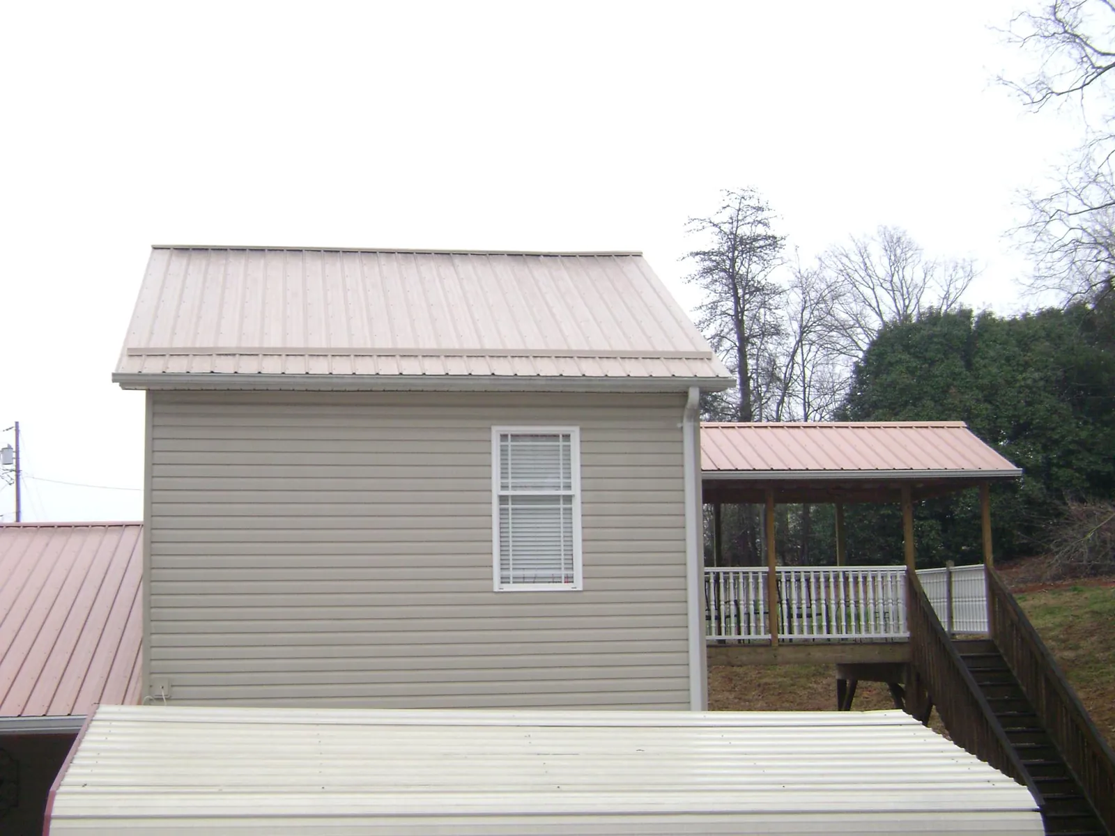 Tan metal roofs on a two story addition and attached porch, from a Roof Replacement job in Gasburg