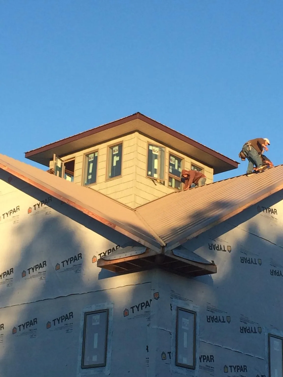 Roofers working around a rooftop cupola on a new metal roof at sunset — Roof Waterproofing in Gasburg by Roofing Brothers